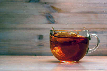 Adding lemon to tea in transparent cupの写真素材