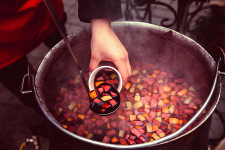 Hand pours mulled wine from bowl into glassの写真素材