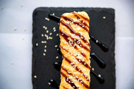 Freshly cooked uncut sushi roll on black boardの写真素材