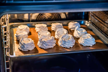 White tasty meringues baking in ovenの写真素材