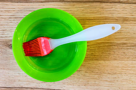 Green bowl with oil and red pastry brushの写真素材