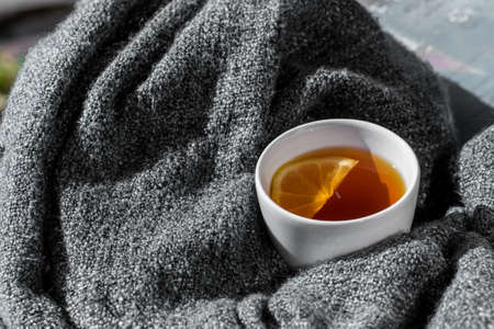 Close up white cup of lemon tea wrapped in blanketの写真素材