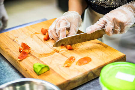 Hands in gloves cut vegetables