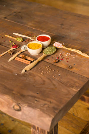 Close up wooden bowls and spoons filled with paprika, rosemary, pink salt and turmericの写真素材
