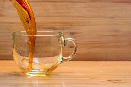 Close up black tea poured in transparent teacup on wooden backgroundの写真素材