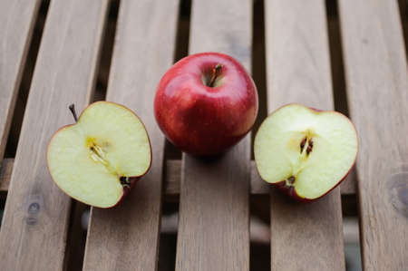 Apples whole and cut in halves on wooden surface