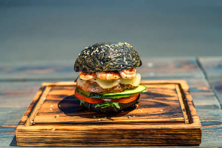 Black burger with prawns on wooden boardの写真素材