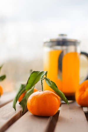 Glass teapot with orange drink and tangerinesの写真素材