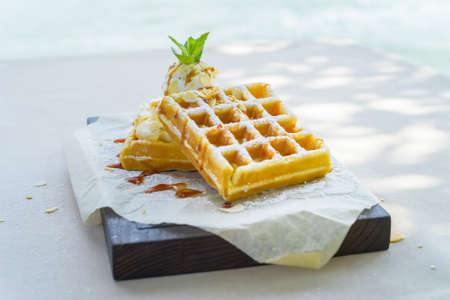 Close up delicious belgian waffles with ice cream, syrup and nuts on napkinの写真素材