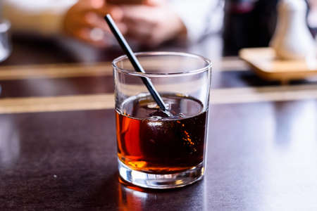 Close up restaurant table with glass of cola and whiskey and straw