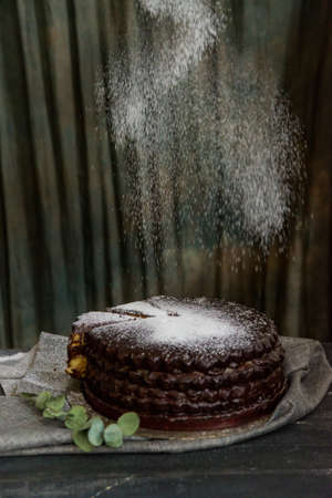 Covering chocolate cake with sugar powderの写真素材