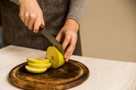 Woman cuts green apple on board closeの写真素材