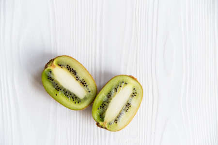 Two halves of kiwifruit on white wooden surfaceの写真素材