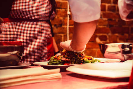 Hand in glove mixes salad with meatの写真素材