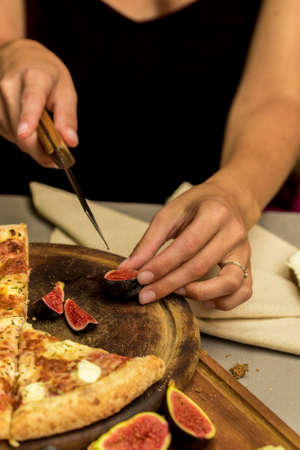 Close up female hands cutting fig with knife