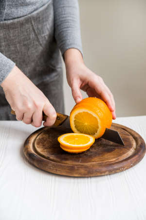 Woman cuts orange on board closeの写真素材
