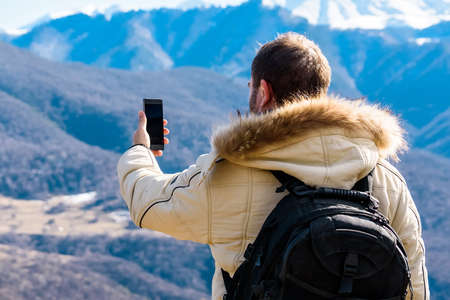 Male photographer in winter mountrains back viewの写真素材