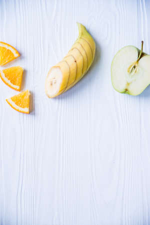 Sliced apple, orange and banana on a white wooden table backgroundの写真素材