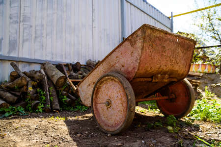 Old rusty wheelbarrow in gardenの写真素材