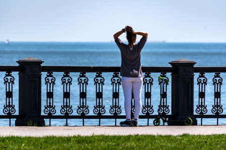 Young sporty woman looks at sea back viewの写真素材