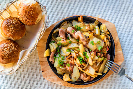 Roasted potato in frying pan with meat and green leekの写真素材