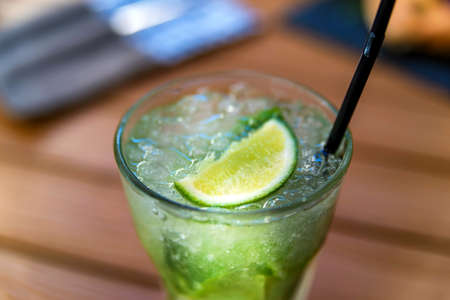 Mojito cocktail with lime and mint in glass on wooden table