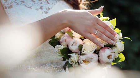 Beautiful bride holds wedding bouquet close upの写真素材