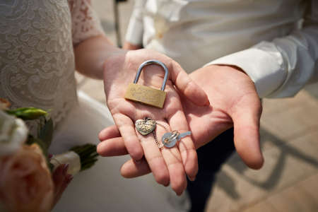 Wedding padlock on hand of bride and groom close up
