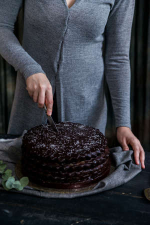 Woman cuts chocolate cake close. Dark tonesの写真素材
