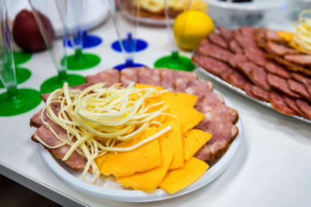 Slices cheese and meat on plate on dinner tableの写真素材