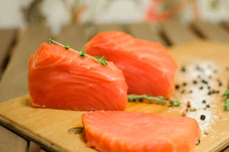Sliced salmon fillet, herbs and pepper on boardの写真素材