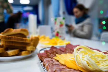 Slices cheese and meat on plate on dinner table
