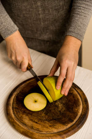 Close up female hands slicing green apple with knife into piecesの写真素材