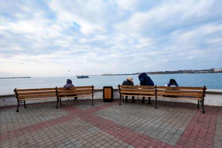 People sit on benches on embankment of Sevastopol in winterの写真素材