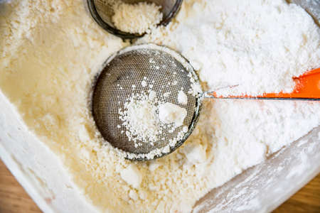 Close up plastic container filled with sugar powder and two sifters in itの写真素材