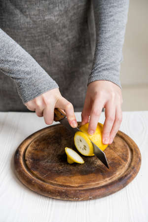 Close up female's hand slicing lemon on wooden boardの写真素材
