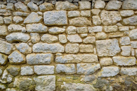 Closeup of beige rough uneven actique stone wallの写真素材