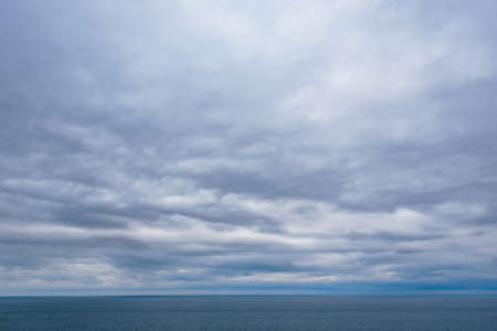 View of calm sea and grey cloudy skyの写真素材