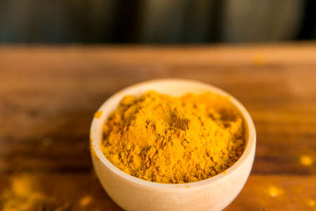 Turmeric powder in bowl on wooden tableの写真素材