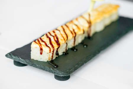 Putting sauce on uncut Japanese sushi rollの写真素材