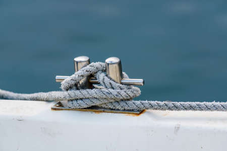 Close up of boat rope tied to nautical cleat hitch on boat