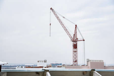 Tower crane at construction site against grey skyの写真素材
