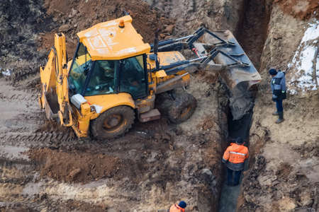Excavator works near trench on construction siteの写真素材
