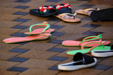 Several pairs of flip-flops next to open pool in winter