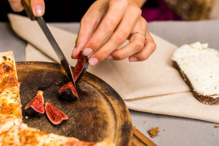 Close up female hands cutting fig with knife