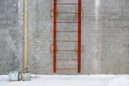View of red metal ladder outside of a concrete buildingの写真素材