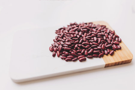 Red kidney beans on white background - A vivid red kidney beans is scattered on a wooden cutting board, emphasizing their rich color and nutritional benefits for various dishes