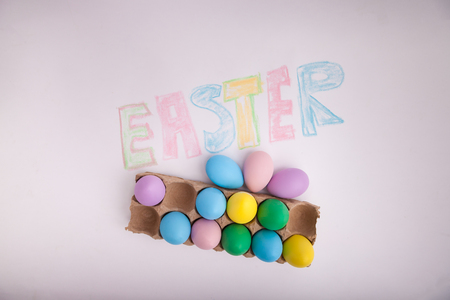 Easter written in chalk with pastel colored Easter eggs in egg cartonの写真素材