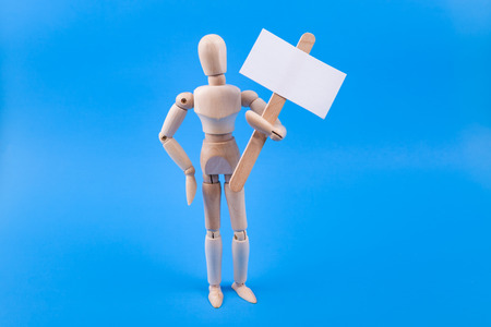 emotionless wooden jointed mannequin holding a blank picket protest sign