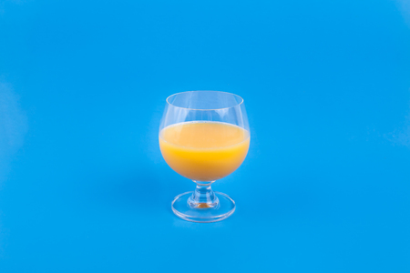 Fancy glass of orange juice on solid blue backgroundの写真素材
